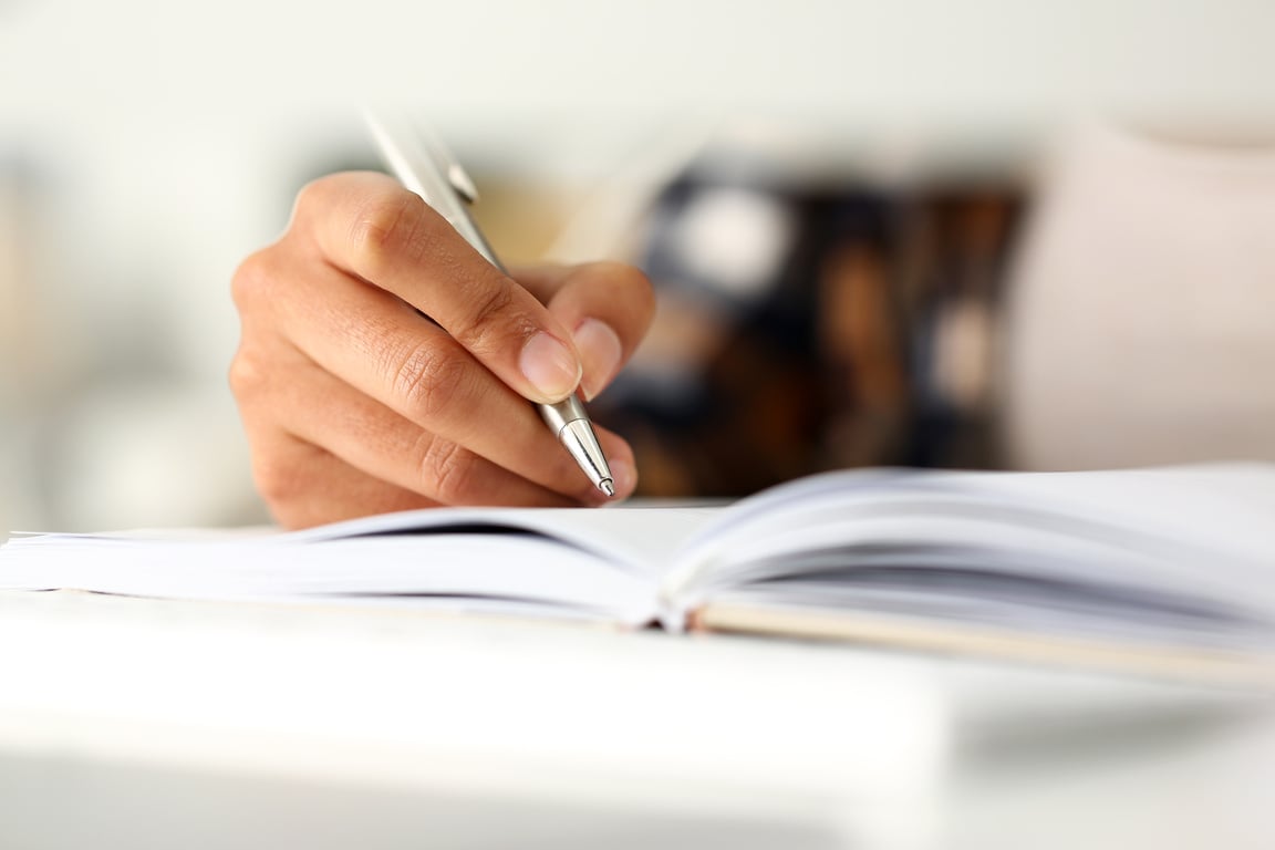 Arm of black woman write story in notebook